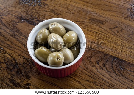 Green olives stuffed with blue cheese in a red and white bowl.