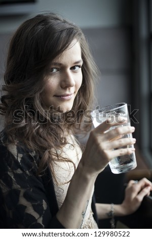 Portrait of a young woman drinking a pint glass of ice water.