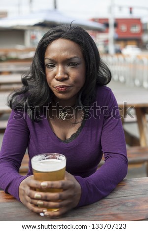 Very unhappy young African American woman and a pint of pale ale.