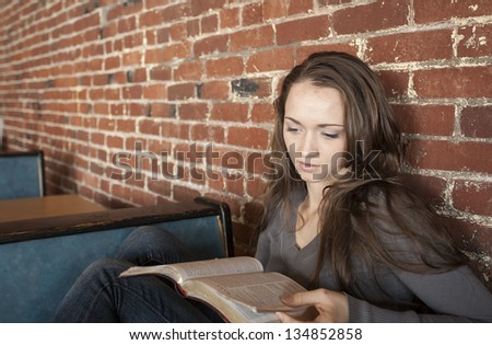 Portrait of a young woman with a white coffee cup reading the book of Mark in the Bible