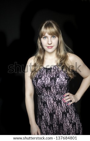 Portrait of a beautiful blond woman in a pretty dress on a black background.