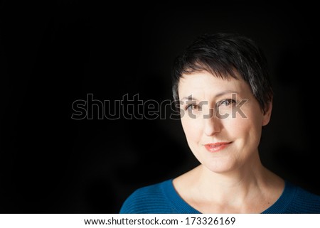 Beautiful older woman with short brown hair and eyes on a black background.