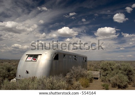 Photo of a vandalized mobile home left out in the desert.