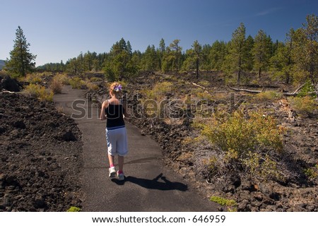 Photo of a girl walking through lava rocks at the Lava Cast Forest, Newberry National Volcanic Monument, near Bend, Oregon, USA
