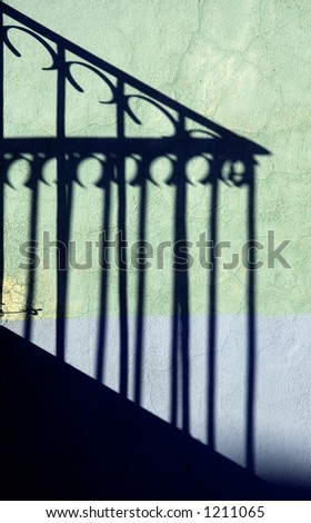 Photo of shadows from wrought iron railing on brightly painted wall