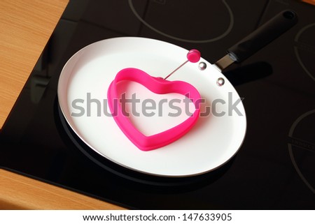 Preparing for frying eggs. Silicone Heart Shape Egg Ring on Frying Pan.