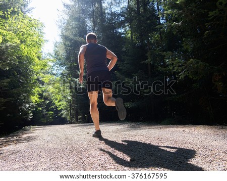 Man running in forest. Rear view.