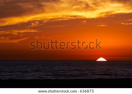 Sun setting on the horizon with ocean waves in the foreground