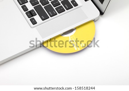 Silvery laptop with yellow dvd disk in slot-loading