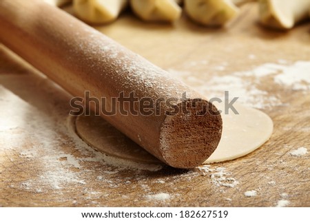 Wooden rolling pin with remnants of flour and stretched dough