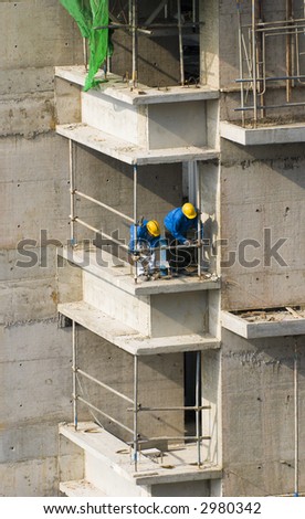 Workers erecting a safety barrier at a construction site for high-rise residential apartment block