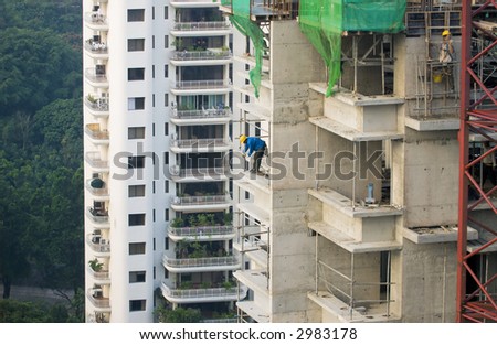 Workers at a construction site for high-rise residential apartment block.  A safety guard rail is being erected.