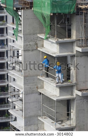 Workers erecting a safety barrier at a construction site for high-rise residential apartment block