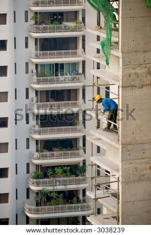 Worker erecting a safety barrier at a construction site for high-rise residential apartment block
