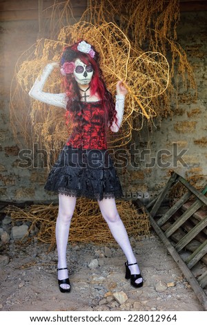 Gothic Beauty; A lady with Mexican mask on her face posing and holding a withered plant in her hands