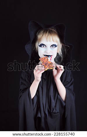 Vampire Child and Gingerbread; A little girl in a fancy dress and a painted face eats gingerbread
