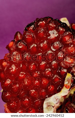 Pomegranate Close-up; a close-up pomegranate fruit with seeds on some lilac studio background