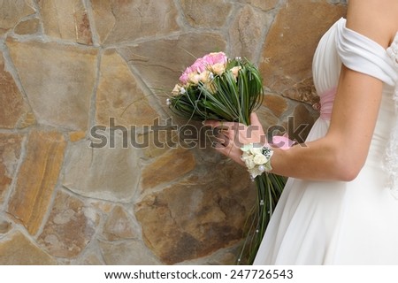 Bridal Bouquet Against Wall; a bride holding her bridal bouquet at a decorated wall