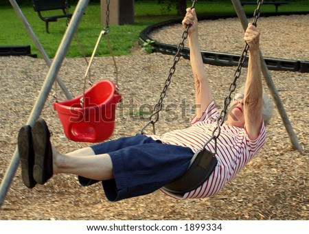 Senior citizen woman on a swing at a playground.