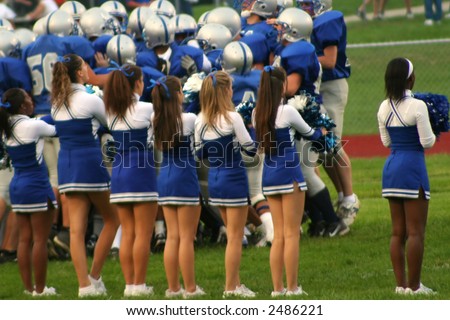 Row of high school cheerleaders welcoming the football team to the field prior to a game.