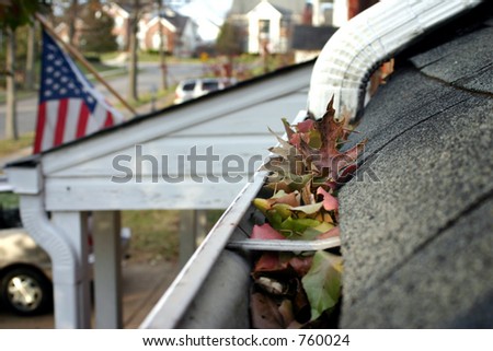 A fall tradition - cleaning the gutters of leaves. Here, we see them clogging the gutters of a traditional home. Narrow DOF used for advertising/clean up articles/etc.