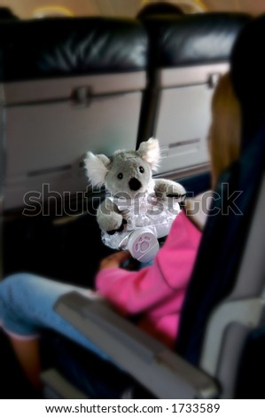 Girl on an airplane with her security bear - focus is on the bear and everything else is out of focus