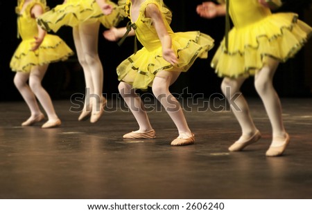 Performing on stage, a group of young dancers show off their talent and bright costumes - image highlights a narrow depth of field