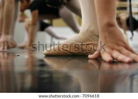 Young dancers are learning - they\'re waiting to see what the instructor says to do next... low angle shot of just their feet and legs - this view has had the color removed from the floor and wall.