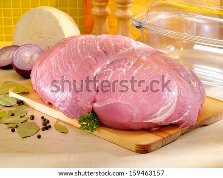 Raw ham on cutting board and glass baking pan. Pork meat in the kitchen.