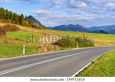 Asphalt Road by The Pieniny Mountains landscape, Carpathians. Daylight scenery with way in the environment of trees, meadows, mountains and clouds on blue sky.
