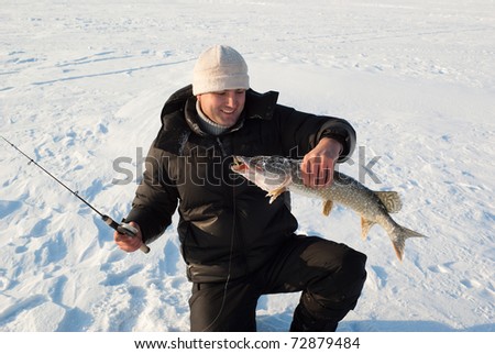 The fisherman  has caught a pike on winter fishing. Russia, Transbaikalia.