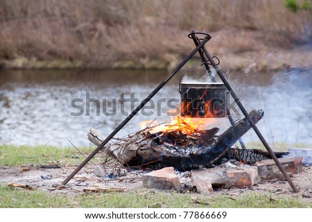 Preparing food on campfire in wild camping on pond background