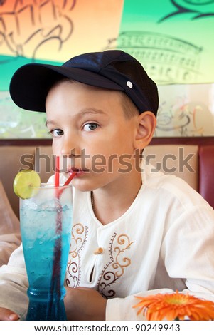 Boy drinks a cold cocktail in cafe