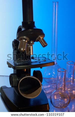 Microscope and laboratory glasswares on a blue background