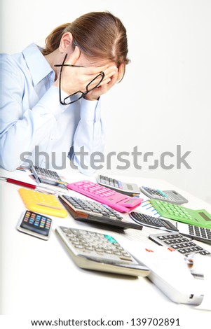 Businesswoman sits at office near calculators and thinks