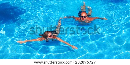 Happy couple swimming in pool. Sport and recreation background