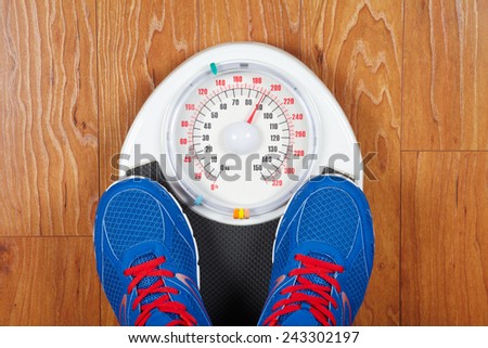 Closeup of man\'s feet on weight scale indicating overweight