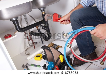 Plumber with Plumbing tools on the kitchen. Renovation.