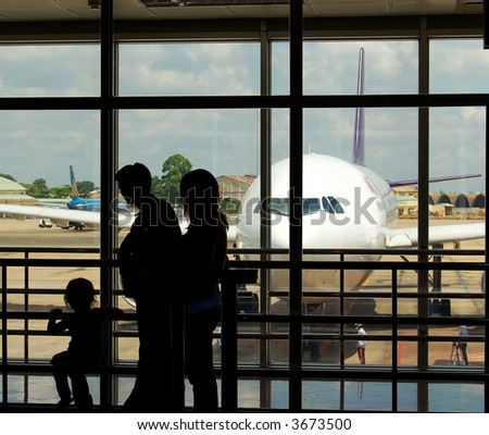 a family at an airport terminal with airplane in the background