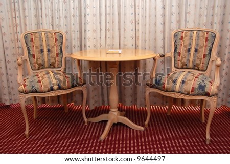 classy interior- two chairs and table placed against drawn curtains