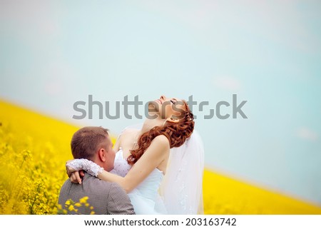 The bride and groom on their wedding day in a field of yellow flowers