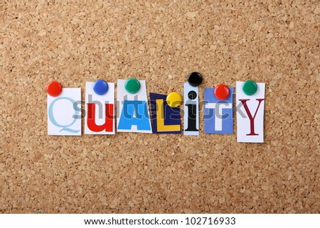 The word Quality in cut out magazine letters pinned to a cork notice board