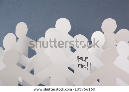 Rows of white paper people chains and one individual has the words Help Me written on it. Concept image for stress,mental health, coping with modern life or looking for help to escape the herd.