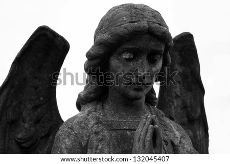 Black and white image of a statue in the form of an angel with her hands clasped in prayer