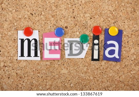 The word Media in cut out magazine letters pinned to a cork notice board with multicolored drawing pins