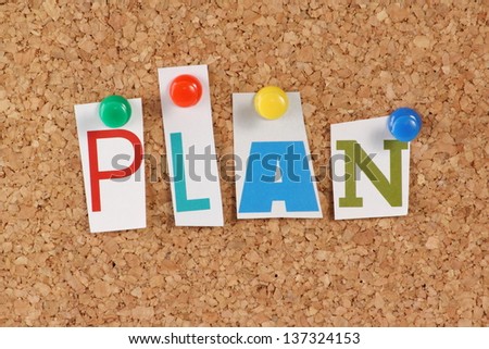 The word Plan in cut out magazine letters pinned to a cork notice board