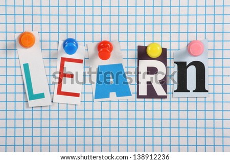 The word Learn in cut out magazine letters pinned to a background of blue graph paper