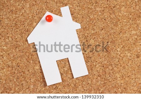 A white paper cut out in the shape of a house and pinned to a cork notice board