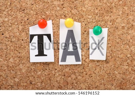 The word Tax in cut out magazine letters pinned to a cork notice board with push pins