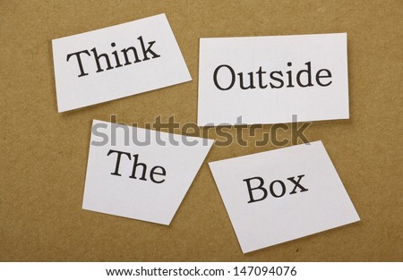 Think Outside the box in cut out text on a background of brown cardboard. The well known phase applies to creative thinking and finding alternative solutions in both business and everyday life.